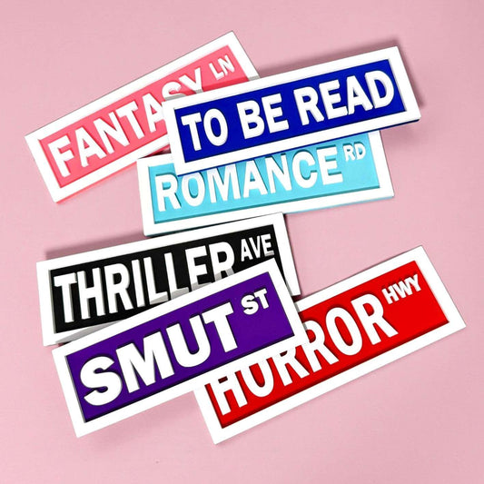 Colourful book genre bookshelf desk decor on a pink background