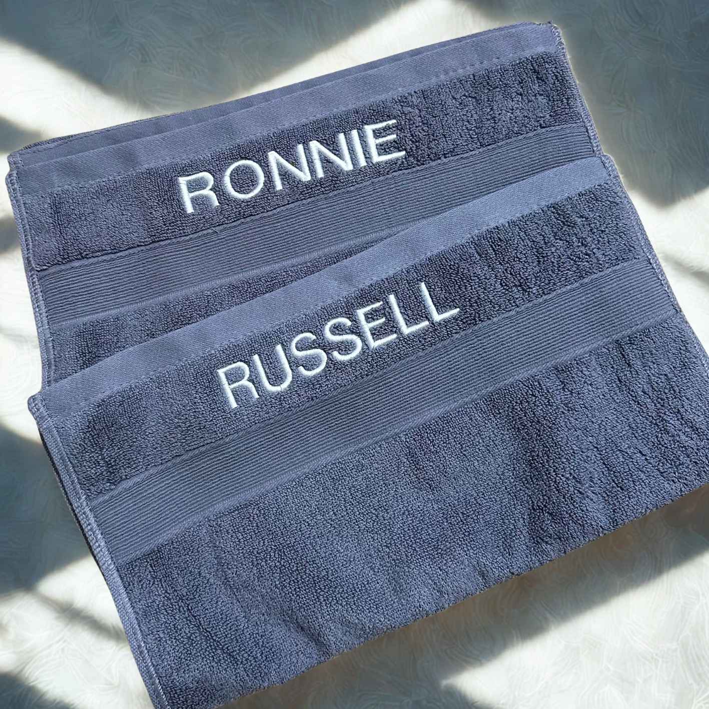 Two blue towels with embroidered with names on a light background.