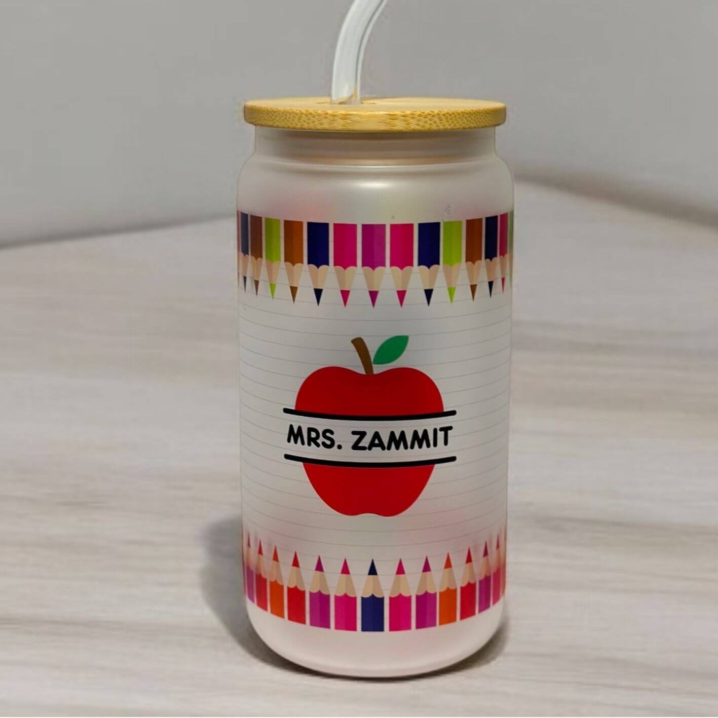 Personalised teacher appreciation glass can displaying custom name, apple design, and motivational education quote with colourful crayon border perfect for end of the year gifting.