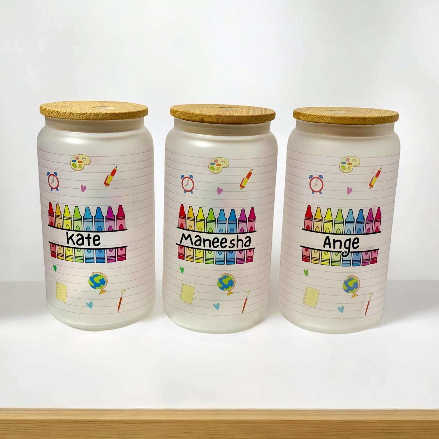 Custom teacher glass can tumblers displaying personalised names and educational themed graphics including crayons, paint palette, and school supplies - handmade teacher gifts