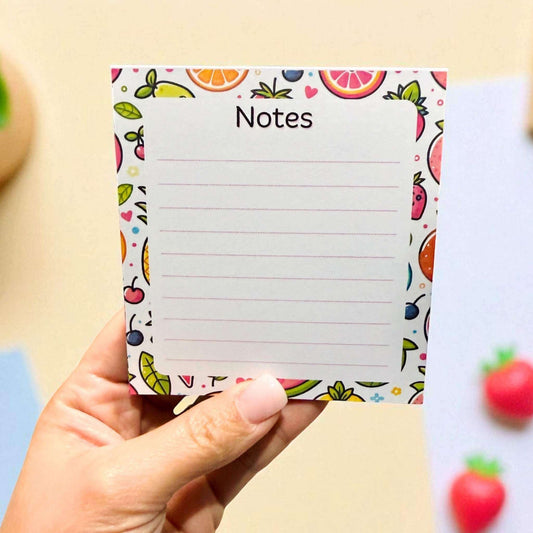 Hand holding custom fruit-themed notes pad featuring colourful citrus, strawberry, and berry border design with lined writing space - cute stationery Australia wide shipping