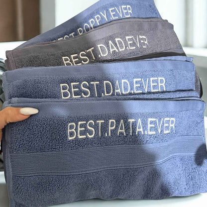 Stack of towels with embroidered text on a neutral background