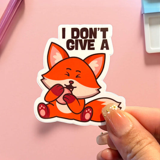 Sticker of a fox with 'I Don't Give A Fox' text held by a hand on a pink background