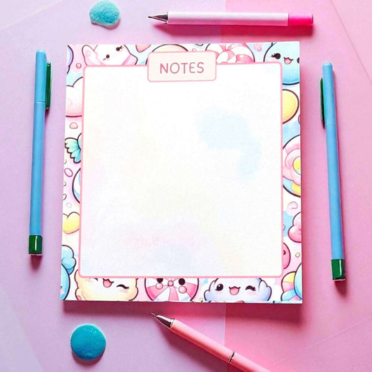 Handmade kawaii-themed notes notepad with cute cartoon characters and pastel colours surrounded by colourful writing accessories - cute stationery