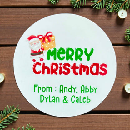 Round Christmas card with Santa Claus and gift, personalized text on a wooden background with Christmas decorations.