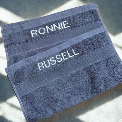 Two blue towels with embroidered with  names  on a light background.