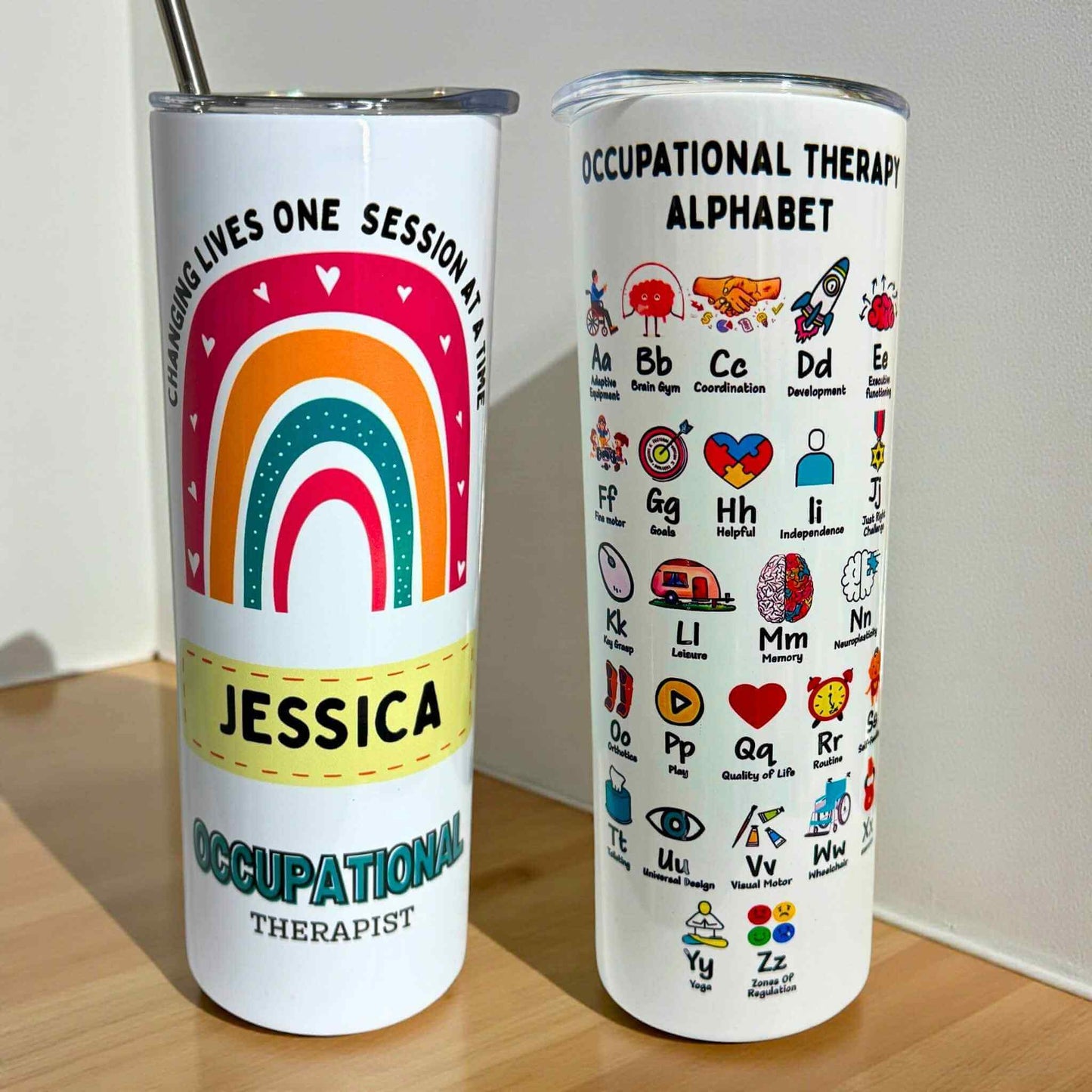 Two tumblers; one with a rainbow design and text, the other with occupational therapy alphabet design.