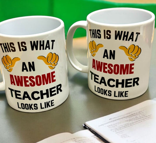 Two white mugs with humorous text and graphics on a table, this is what an Awesome teacher look like writing