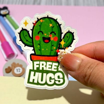 Sticker of a cactus with 'FREE HUGS' text held by a hand on a colorful background.