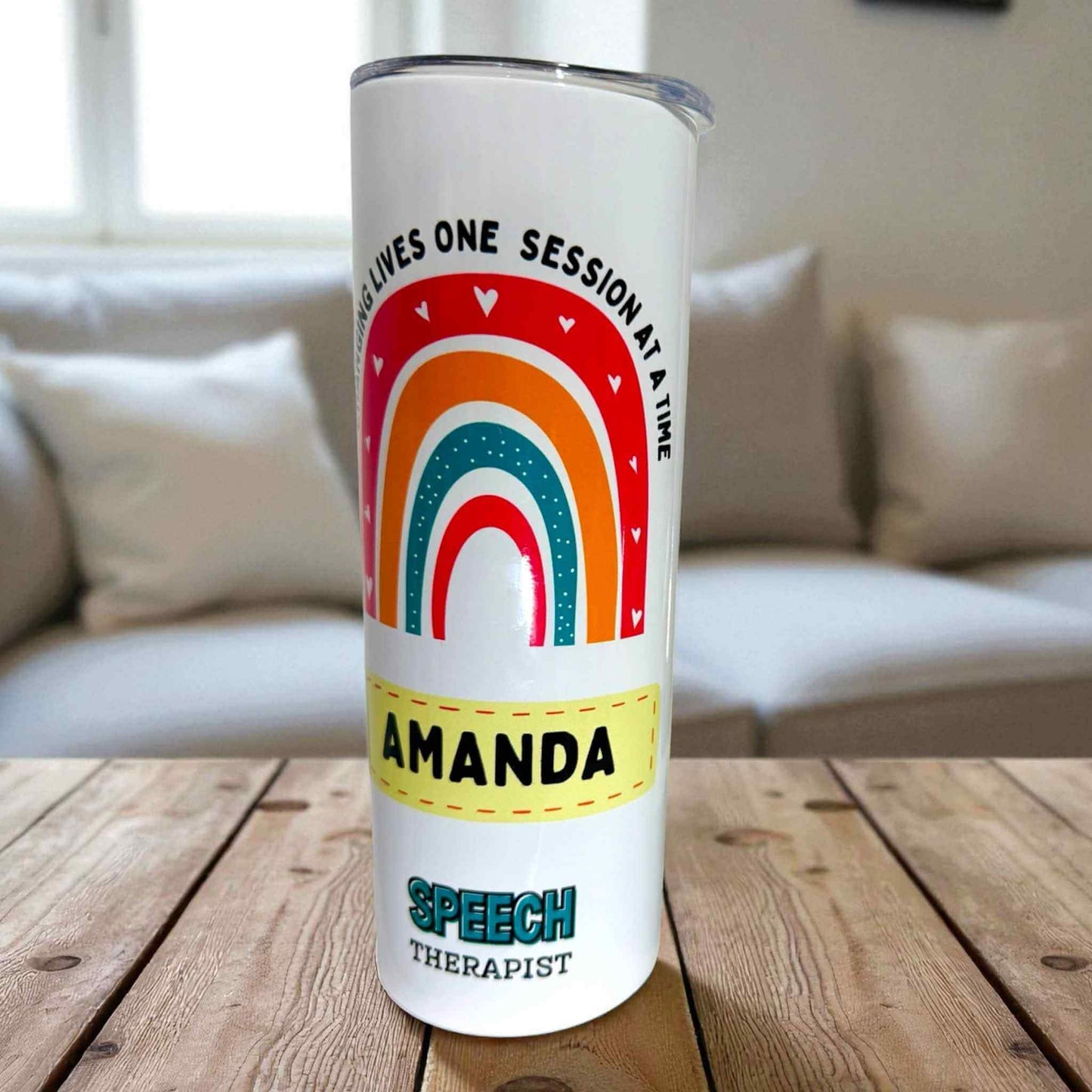 Tumbler with rainbow design and text on a wooden surface