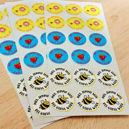 Sheets of colourful teacher praise stickers with phrases like ‘Donut Give Up’, ‘Berry Good’, and ‘Bee-utiful Work’